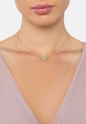 Collar de oro con un colgante floral que presenta una piedra central de color turquesa, montado en una delicada cadena. Diseño simple y elegante.