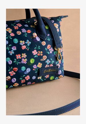 Tumed floral print kott, mis on valmistatud sünteetilisest materjalist, käes värvikad lilled ja kommimotiivid, kuldne riistvara ja brändi silt.