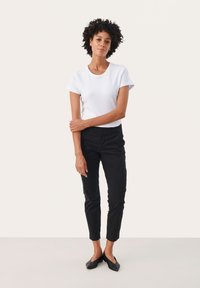 White fitted t-shirt with short rolled sleeves, paired with black ankle-length pants and black pointed flats. Simple design with no patterns.