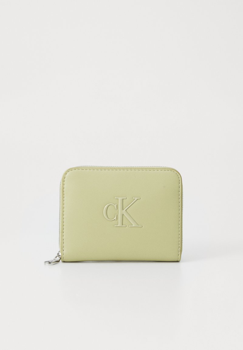 Hele roheline kompaktsest rahakotist, millel on lukuga sulgemine ja kolmemõõtmelise "cK" logo esiküljel, valge tausta ees.