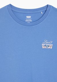 Blå Levi's t-shirt med rund halsringning och liten broderad logotyp med bergs- och blommönster på vänster bröst.