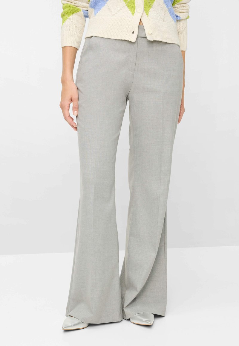 Grå, udvidede bukser med en tekstureret stof, der har en glat talje og diskrete folder ned foran, kombineret med spidse sko.