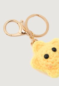 Keyring with gold metal clasp and ring attached to a yellow crocheted star-shaped charm with two black bead eyes.