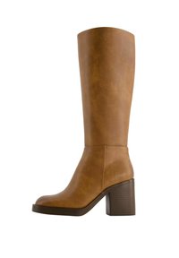 Brun läderknäboots med rund tå, kraftig texturerad klack, slät yta och minimala sömdetaljer.