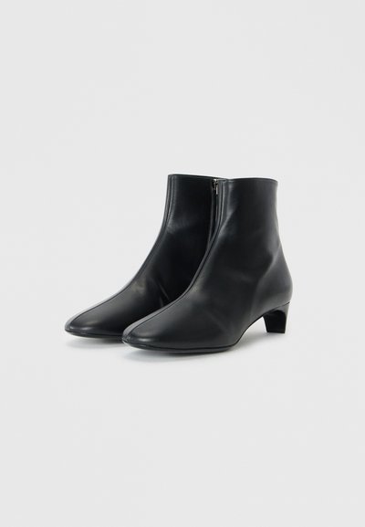 Bottines en cuir noir avec un bout pointu, texture lisse, fermeture éclair sur le côté et un design à petit talon carré.
