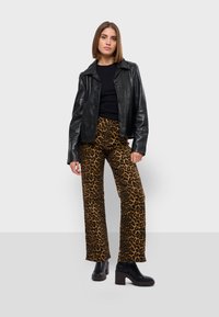 Černá kožená bunda, fitted, s knoflíky; černý top; hnědé široké kalhoty s leopardím potiskem; černé platformové kotníkové boty; hladké textury.