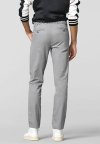 Grijze katoenen broeken met een rechte snit, voorzien van twee achterzakken en een geborduurde tailleband, gedragen met witte sneakers.