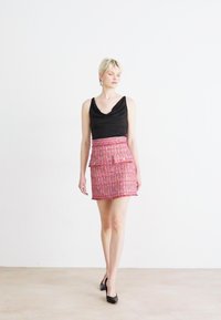 Juoda be rankovių palaidinė su iškirpimu, derinama su rožiniu tweed mini sijonu, kuris turi kišenes ir paspaudimo akcentus.