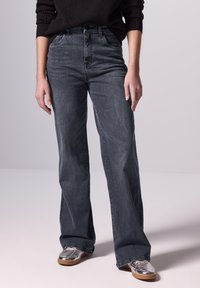 Donkergrijze wijde jeans gemaakt van denim, met een knoopsluiting, zijzakken en een gladde textuur met minimale vervaging.