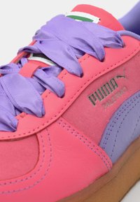 Sneaker with pink leather upper, purple laces, and gray accents. Features Puma logo and "Palermo" branding, textured rubber sole.