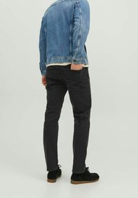 Jeansjacka i ljusblått med klassisk skärning, kombinerad med svarta slim-fit byxor och svarta mockaskor, som visar en avslappnad stil.