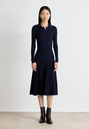 Navy ribbed knit dress with a polo collar, long sleeves, and pleated skirt. Paired with chocolate brown ankle boots.