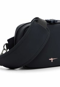 Melna pleca soma no gluda materiāla, ar lielu siksnu un smalku roze zelta krāsas logo akcentu. Rāvējslēdzēja slēgums redzams augšpusē.