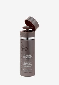 Brown plastic bottle with a pump dispenser, silver band, and lid. Label reads "SARAH CHAPMAN London SKINESIS Lash Boosting Eye Cleanse."