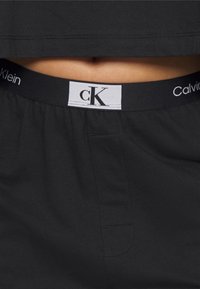 Shorts noirs Calvin Klein avec une taille élastique ornée du logo, en tissu doux, et un design simple et décontracté.