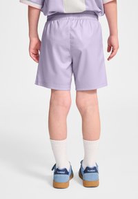 Lavendelf�ärgade shorts i lätt tyg med elastisk midja, parat med blå sneakers och vita strumpor, som visar en avslappnad passform.