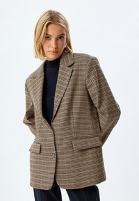 Karierter Blazer mit einem braun, rot und grünem Muster, strukturiertem Design, Reverskragen, zwei vorderen Taschen und Knopfverschluss.