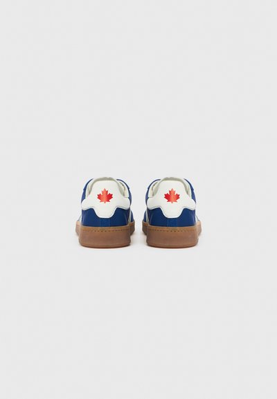 Kék sportcipők fehér részletekkel és piros juharlevelet mintázó díszítéssel a saroknál, barna gumitalppal.