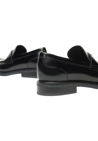 Scarpe in pelle nera con finitura lucida, profilo basso e tacco leggero. Presentano bordi curvi e dettagli di cucitura sobria.