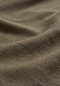 Brązowy, teksturowany materiał zaprezentowany w fałdach, charakteryzujący się miękką, tkana powierzchnią z delikatnym wzorem. Materiał wydaje się lekki i elastyczny.