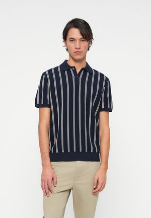 Polo cu dungi navy, cu linii verticale albe, mâneci scurte și guler cu nasture; textură ribbită și croială ajustată în talie.