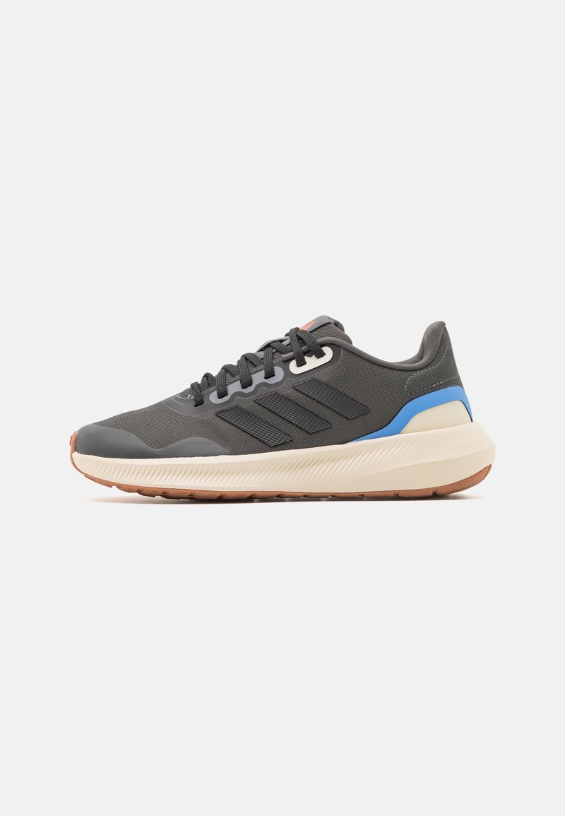 Zapato deportivo gris con una parte superior texturizada, detalles en azul y una entresuela de color claro. Cuenta con una suela acolchada y una suela exterior con patrón.