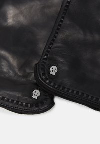 Schwarze Lederhandschuhe mit sichtbaren Nähten und silbernen Schädelakzenten an den Bündchen. Glatte Textur mit einer taillierten Passform.