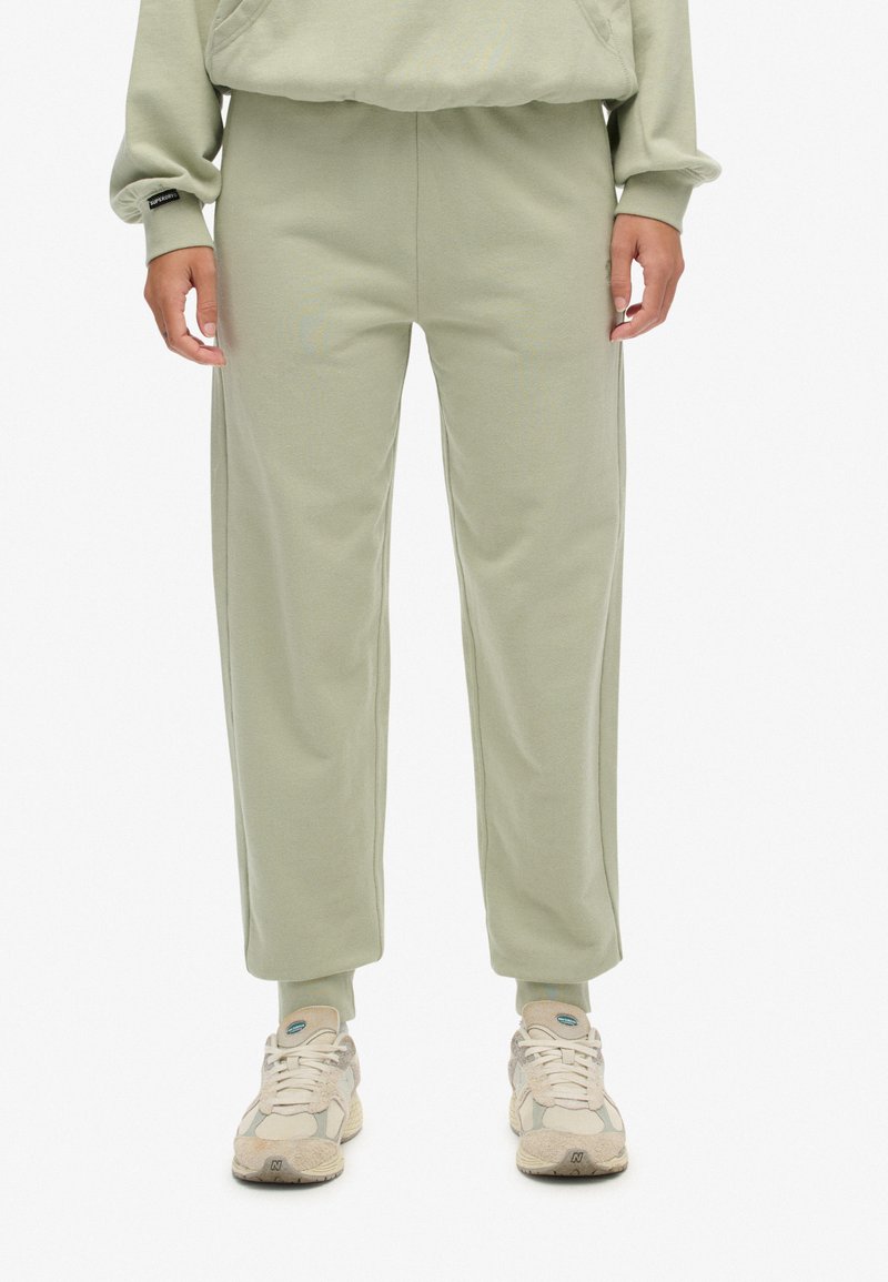 Lysegrøn sweatpants lavet af blød stof, med elastisk talje, tapered ben og sømmede ankler. Parret med beige sneakers.
