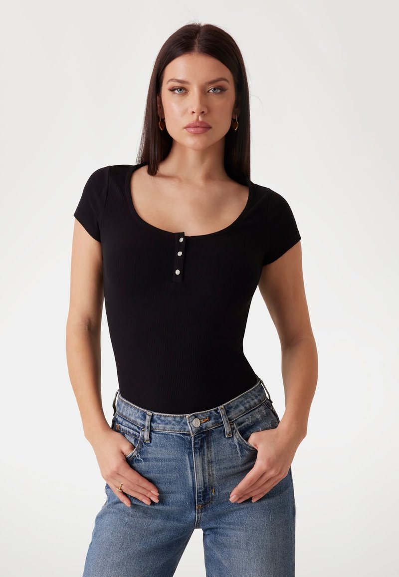 Svart ribbestrikket bodysuit med korte ermer og scoop-hals, med tre sølvfargede knappdetaljer foran.
