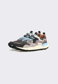 Des baskets en maille et suédine grises et beiges, avec des accents noirs, des lacets bleu clair, et une semelle blanche texturée avec un motif de relief.