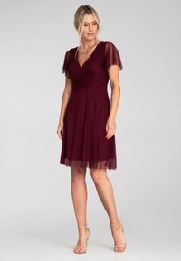 Bordeauxfarbenes Kleid mit kurzen, transparenten Ärmeln, V-Ausschnitt und plissiertem Oberteil. Ausgestellter Rock mit einem geschichteten Tüllsaum, strukturierter Stoff.