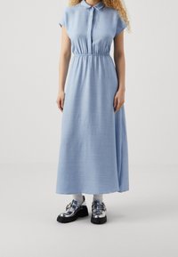Abito maxi azzurro chiaro a maniche corte e colletto con vita elasticizzata, abbinato a scarpe platform argento lucido e calzini bianchi.