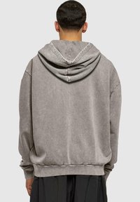 Sudadera con capucha gris de textura suave, corte relajado y puños y dobladillo acanalados. Cuenta con una gran capucha caída para mayor comodidad.