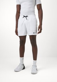 Pantalones cortos deportivos blancos con cintura ajustable, que presentan acentos laterales negros y un pequeño logotipo negro de Nike en la pierna izquierda.