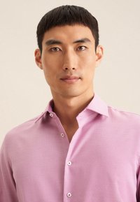 Camicia rosa con una finitura texturizzata, dotata di chiusura a bottoni e colletto a contrasto con motivo. Tessuto morbido e vestibilità slim.