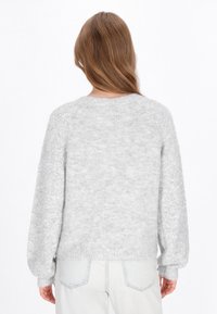 Világosszürke pulóver, texturált, bolyhos testtel és mintázott, puffos ujjal. Egyszerű kerek nyakú kivágás és bordázott szegély.