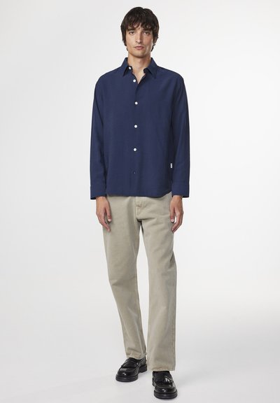 Navy long-sleeve button-up shirt in lightweight fabric, paired with beige straight-leg pants and black shoes, showcasing a classic design.