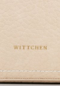 Portefeuille en cuir beige avec une surface texturée. Logo "WITTCHEN" en relief doré et couture blanche en bas. Design simple et élégant.