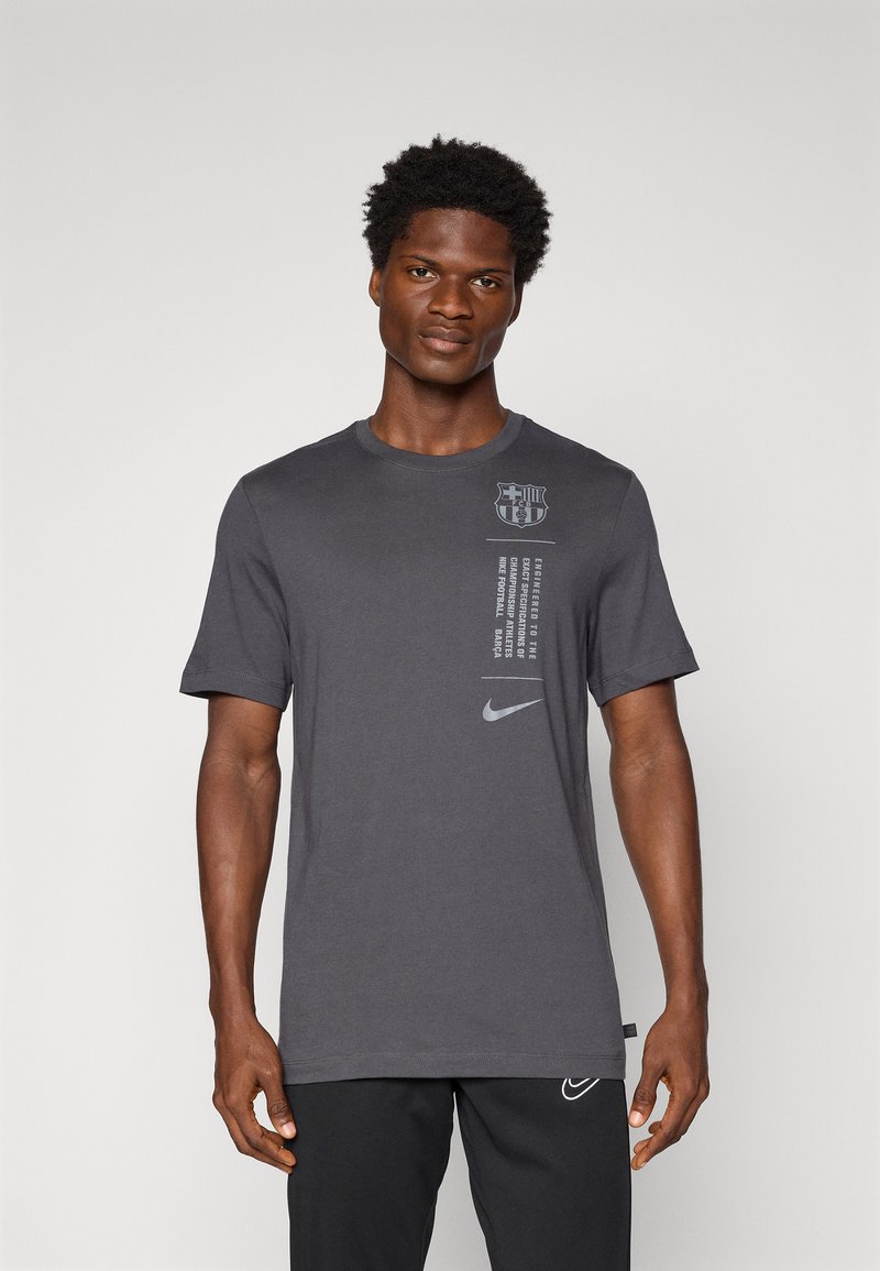 T-shirt en coton gris avec le logo de Barcelone et le swoosh de Nike. Manches courtes, col rond et coupe décontractée avec un texte imprimé sur le devant.