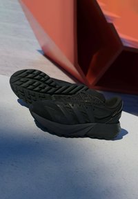 Czarne buty sportowe z teksturowanymi wzorami, amortyzowaną podeszwą oraz wspierającą cholewką wykonaną z materiałów syntetycznych z precyzyjnymi przeszyciami.