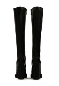 Bottes noires montantes en cuir lisse. Talons épais et hauts, zips sur le côté et silhouette élancée. Semelles en caoutchouc texturé pour une bonne adhérence.