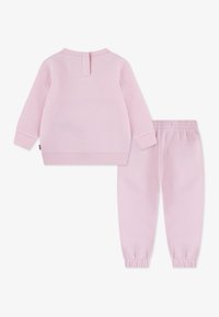 Rosa Sweatshirt mit langen Ärmeln und gerippten Bündchen, kombiniert mit passenden rosa Jogginghosen mit elastischem Bund und gerippten Fußgelenkbündchen.