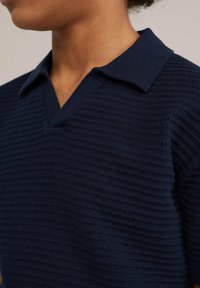 Námornícky pletený polo tričko s textúrovaným povrchom, s výstrihom do V a preloženým golierom. Materiál má ryhovaný vzor.