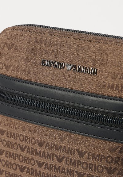 Borsa di stoffa marrone con un motivo logo testurizzato, cerniera nera e un accento del logo del brand in metallo. Il design è rettangolare con superfici lisce.