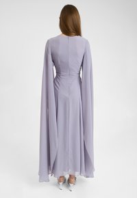 Lila lange jurk met vloeiende chiffon stof, aansluitend lijfje en een licht uitlopende rok. Voorzien van een ritssluiting aan de achterkant.