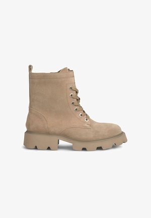Botas de tobillo de ante beige con puntera redondeada, cordones en la parte delantera y tacón grueso. Con ojales de metal y una pestaña en la parte trasera.