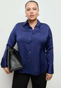 Navy satin long-sleeve shirt with a pointed collar, featuring gold buttons down the front, paired with a textured black handbag.