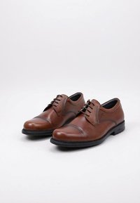 Zapatos de vestir de cuero marrón con punta redonda, con una textura suave, costuras mínimas y cordones. Suela negra con ligera elevación.