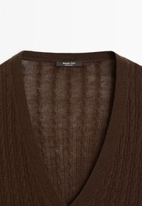 Pull marron à col en V en maille torsadée avec bord-côte, étiquette « Massimo Dutti Made in China » à l’intérieur du col.