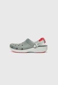 Grauer Clogslipper aus leichtem Material, mit Belüftungslöchern, verstellbarem Fersenriemen und einem roten Akzent an der Rückseite.